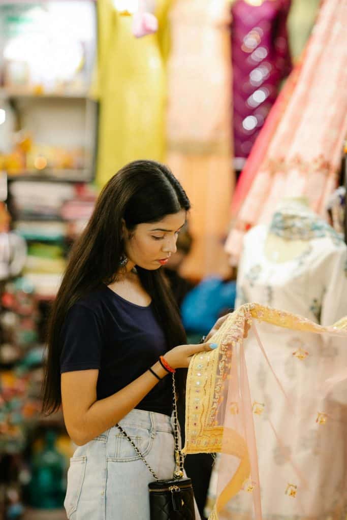 Young adult woman from India looking at fabric in a store.