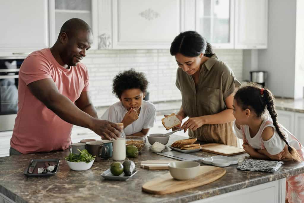 Mom, dad, son, and daughter standing in kitchen making breakfast.
