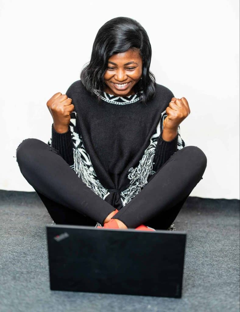 Excited black woman showing yes gesture near laptop