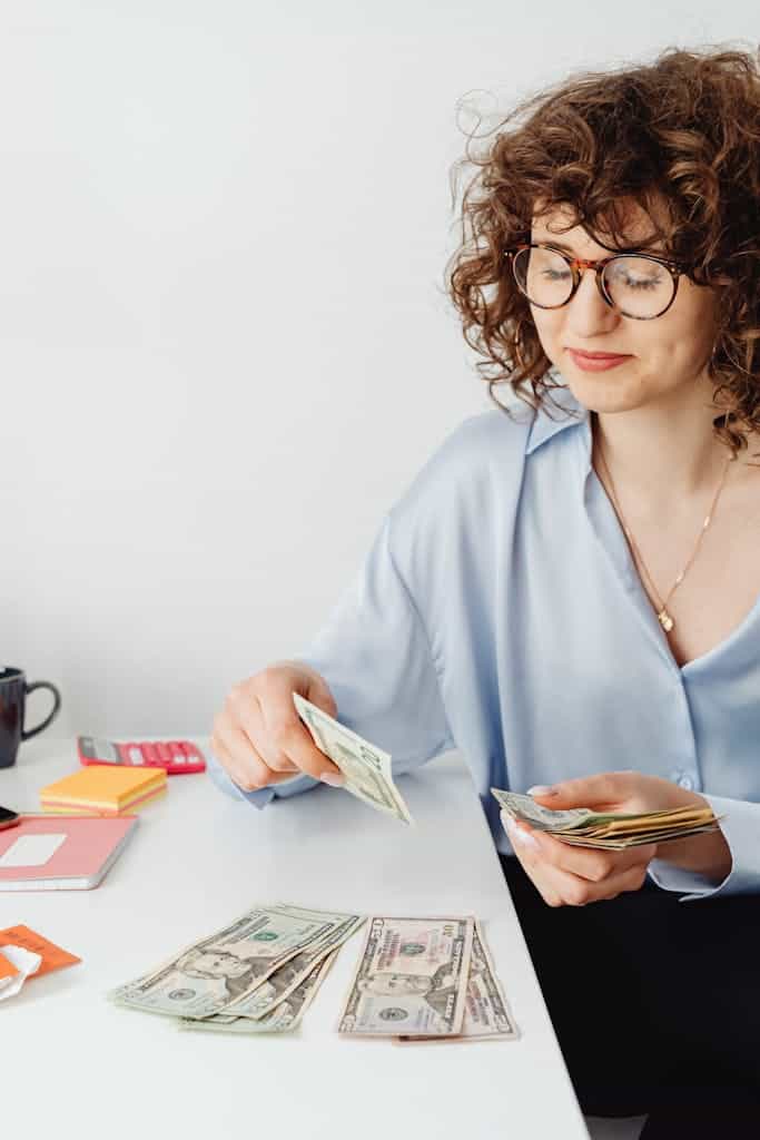 Woman Counting Money on White Table