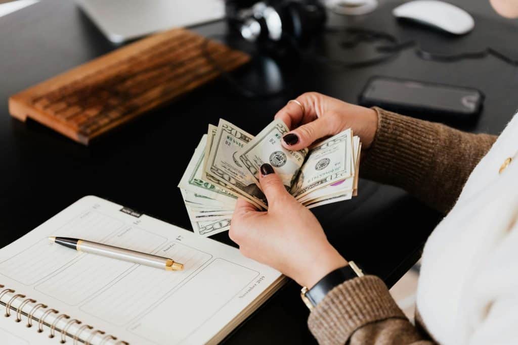 A woman's hands counting money and figuring out her budget to see where she can afford to pay for convenience. 