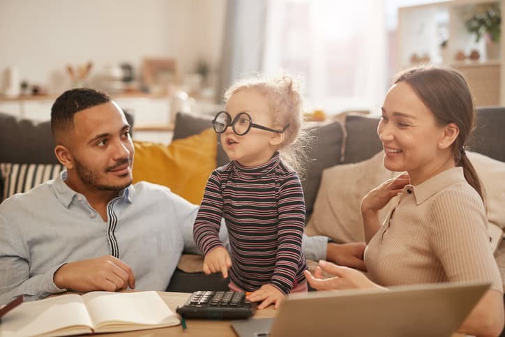 A dad, mom, and little girl weearing glasses upside down pressing buttons on a calculator. 