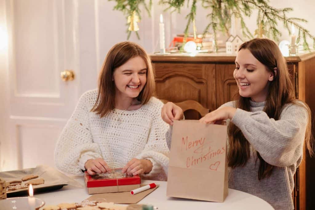 2 girls putting together gift packages of homemade cookies. 