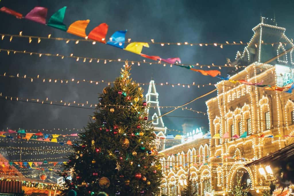 Outdoors in a city that is all decorated for Christmas at night. 