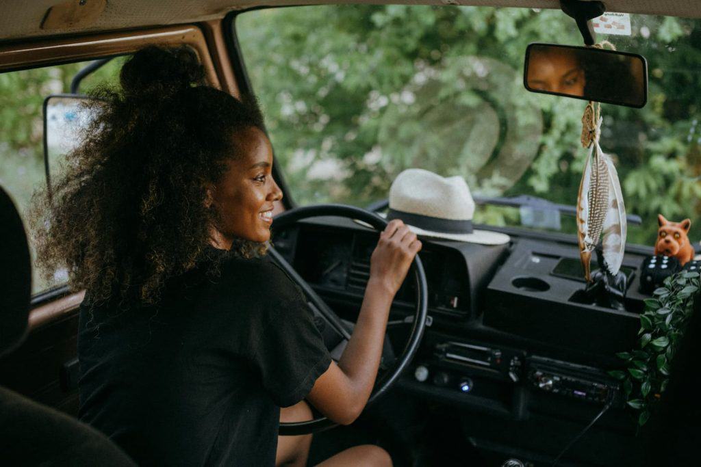 Smiling woman behind the wheel of what looks like an RV.