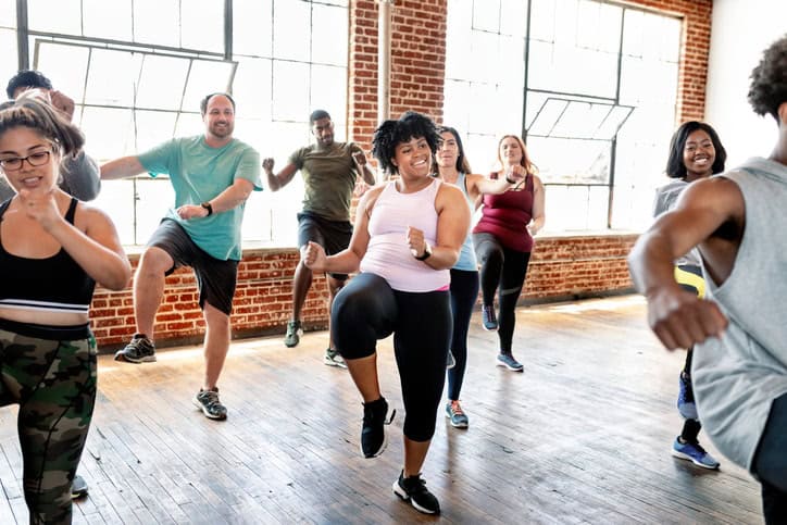 Woman working out in a group exercise class with a smile on her face. 