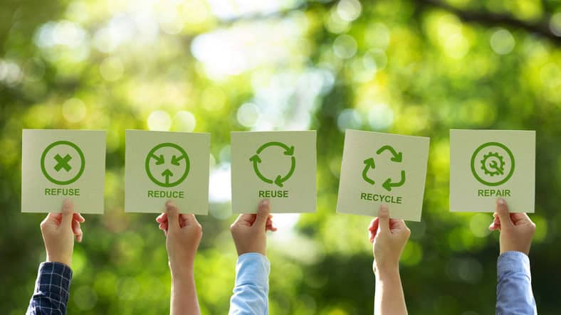 Hands holding up cards that say refuse, reduce, reuse, recycle, and repair.