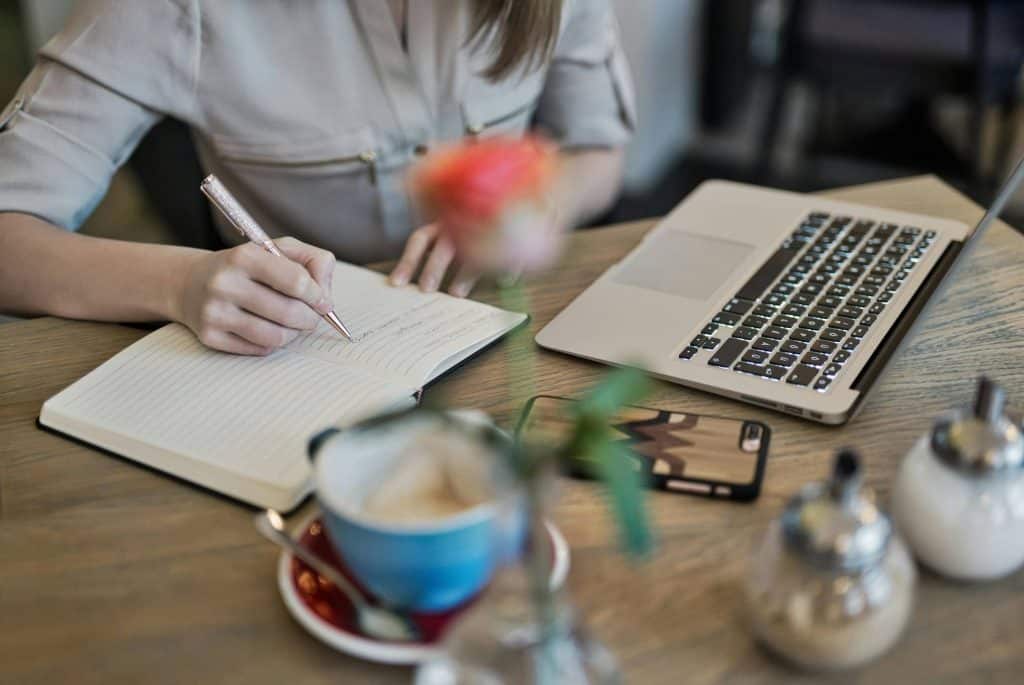 A women sitting at the table writing in a gratitude journal to help improve her money mindset.