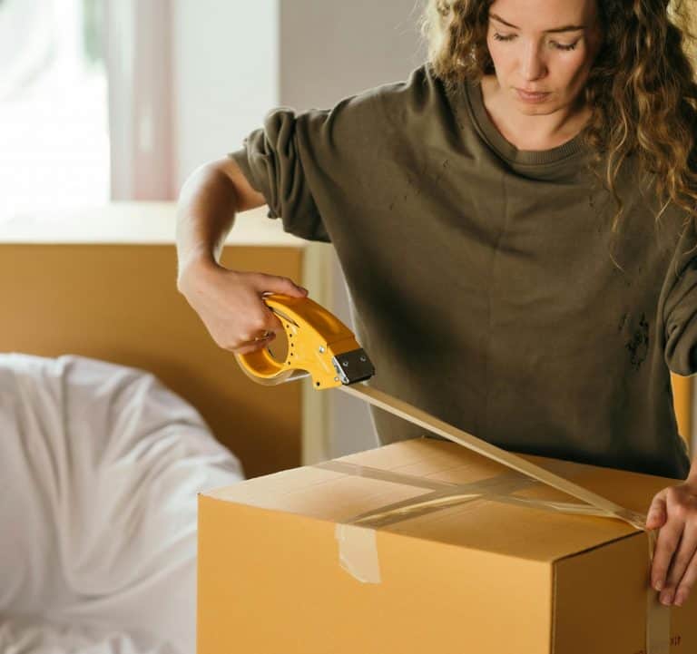 Women putting packing tape on a box she is getting ready to ship from eBay