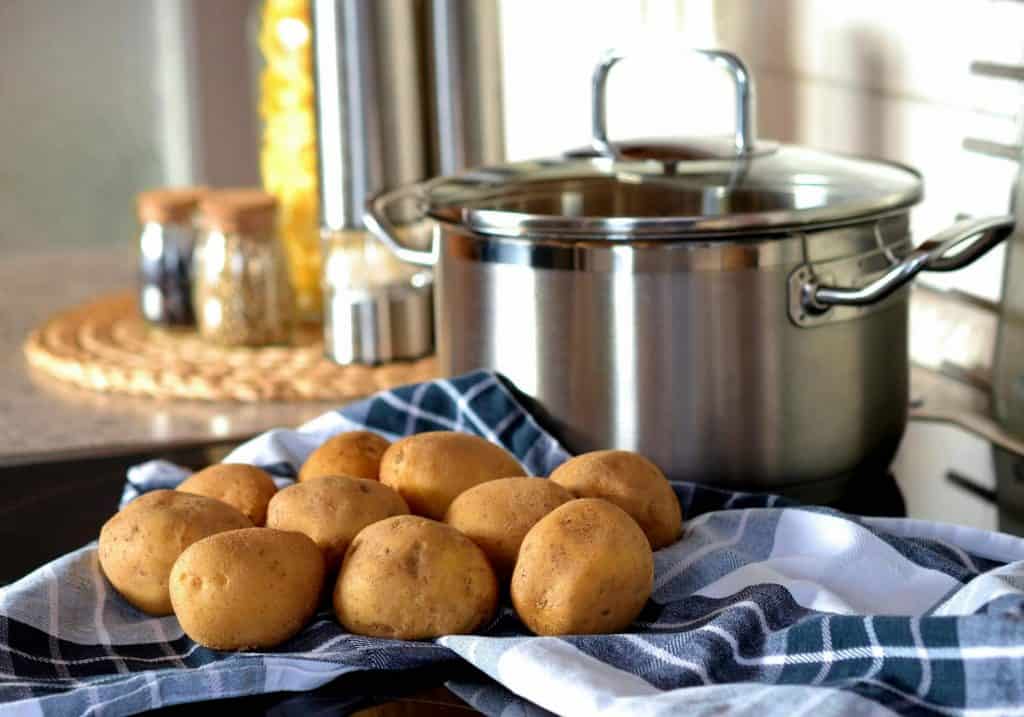 Image of potatoes which are a budget-friendly ingredient sitting next to a pot. 