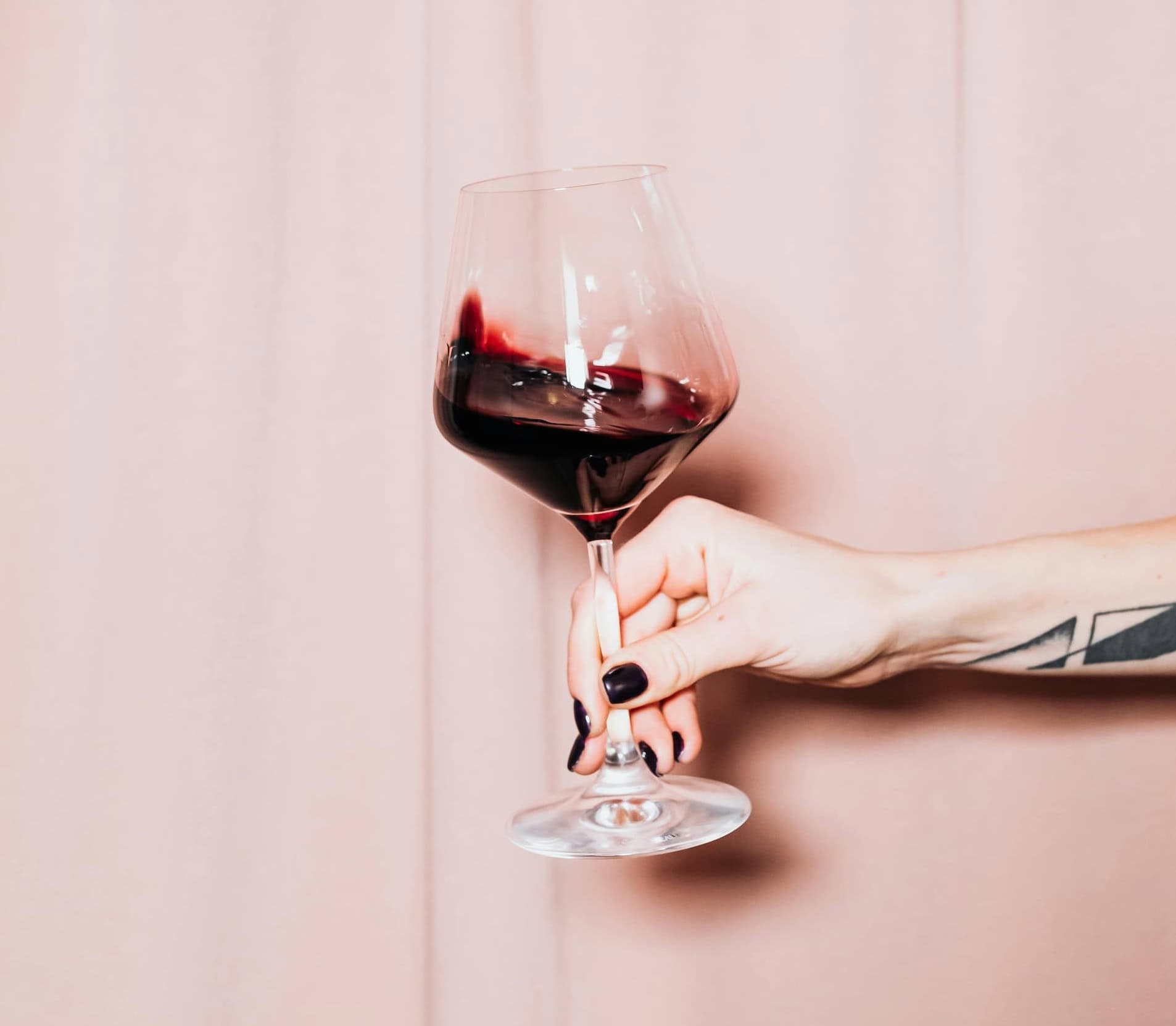 Woman's hand holding a glass of red wine.